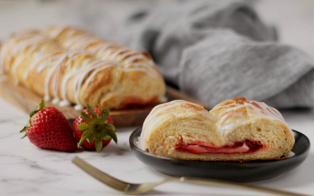 Strawberry Cream Cheese Butter Braid Pastry and slice on plate next to fork and strawberries